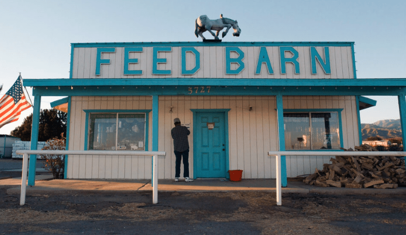 A quaint feed barn nestled in a small desert town, surrounded by arid landscapes and clear blue skies.