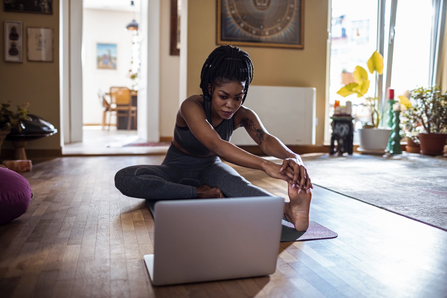 A woman sits cross-legged on the floor, focused on her open laptop, creating a cozy workspace vibe.